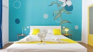 Een hotelkamer met een bed, twee nachtkastjes, een muurdecoratie en een deur.