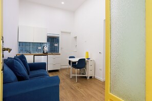 A compact living space with a sofa, a small dining table, and a kitchenette. - Santa Patrizia a Chiaia Apartment  (Naples)