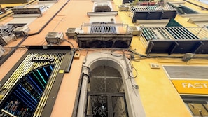 Un edificio con varios balcones, un escaparate visible con un letrero y una ventana con reja de metal.
