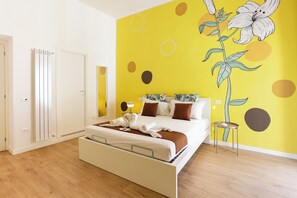 A modern bedroom with a bed, a mirror, a radiator, and a wall with a floral mural. - Santa Patrizia a Chiaia Apartment - Terra (Naples)