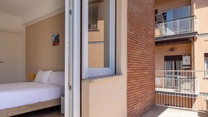Une chambre à coucher avec un lit, une fenêtre et un balcon doté d’une balustrade blanche.