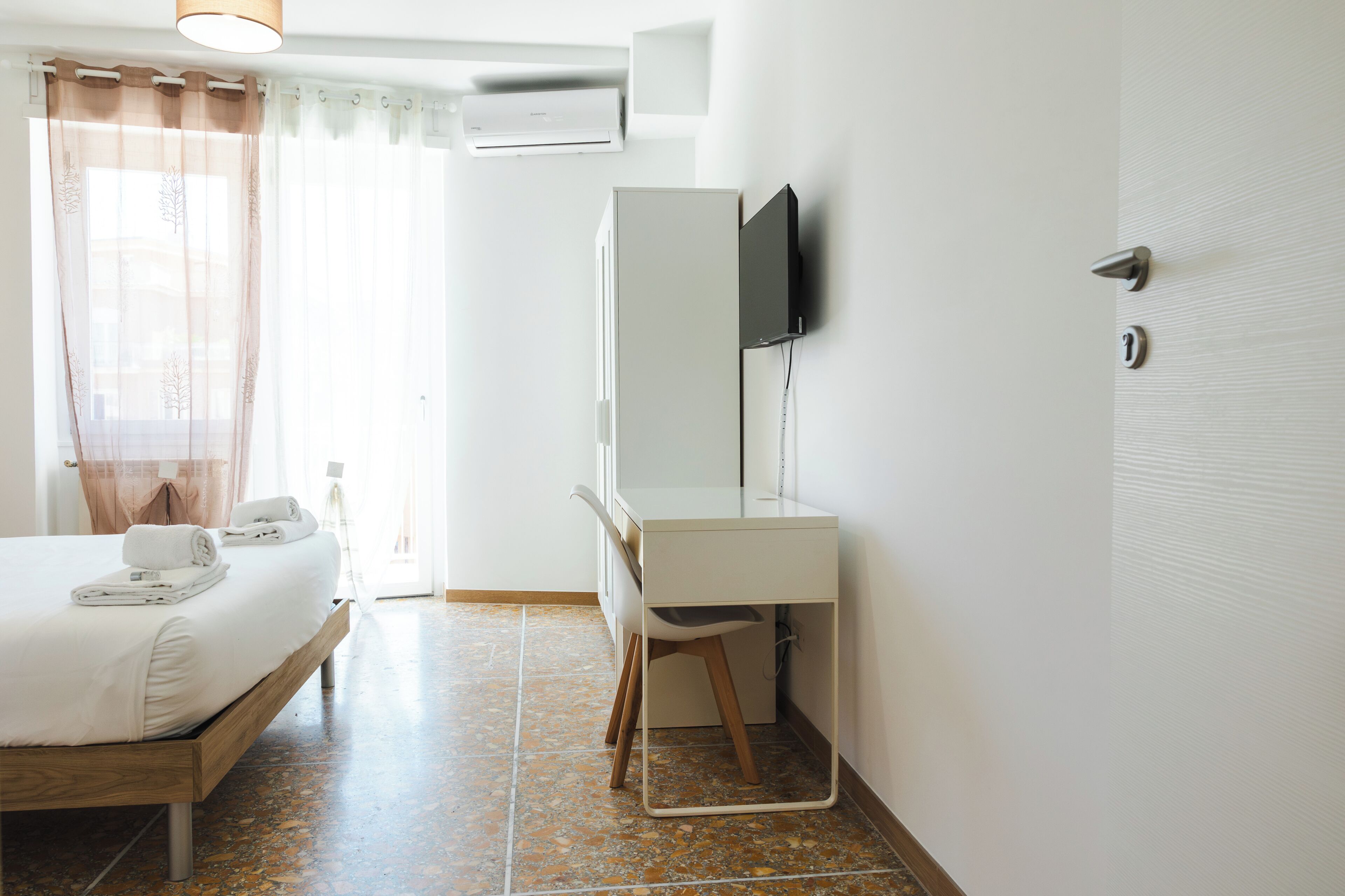 Ein Hotelzimmer mit einem Bett, einem Schreibtisch, einem Stuhl, einem Fernseher und einer Klimaanlage.