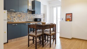 Une cuisine moderne avec des meubles de couleur bleu foncé, un four à micro-ondes et une table à manger avec quatre chaises.
