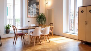 A dining area with a wooden table, white chairs, a potted plant, and a radiator. - Boho 202 (Rome)