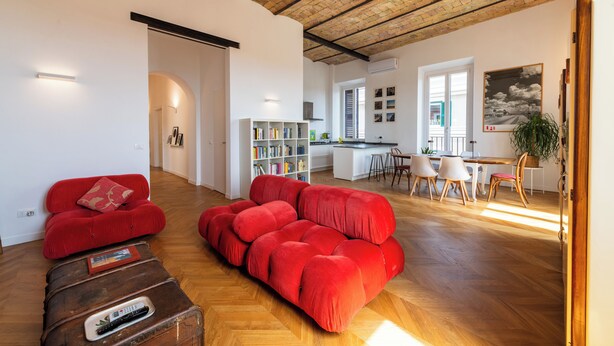A spacious living area with a red sofa, a wooden coffee table, and a kitchen in the background. - Boho 202 (Rome)