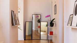 A hallway with a wooden floor, white walls, and a white shelf with framed pictures. - Boho 202 (Rome)
