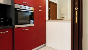 Una cocina con armarios rojos, horno empotrado y cafetera.