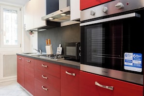 A modern kitchen with red cabinetry, stainless steel appliances, and a window with a view. - Romantic Malatesta (Rome)