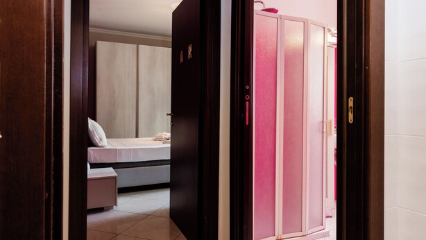 Una habitación de hotel con una cama, una mesita de noche pequeña y un armario.
