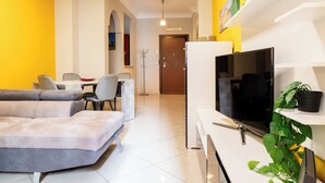 Una sala de estar moderna con un sofá, televisor y un comedor con sillas y una mesa.