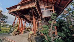 Eine traditionelle Holzhütte mit Balkon, Steinstufen und diversen Pflanzen.