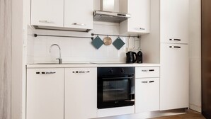 Eine moderne Küche mit weißen Schränken, einem schwarzen Backofen und einer Edelstahl-Dunstabzugshaube.
