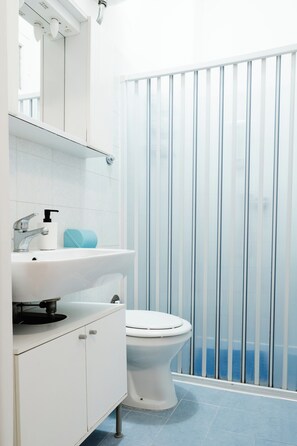 A bathroom with a white sink, a toilet, and a shower curtain. - Montagnola Mini House (Rome)
