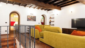 Un salon avec un canapé jaune, un téléviseur et un escalier doté d’une rampe.