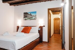 Ein Hotelzimmer mit Bett, einem Holz-Kopfteil, einem Stadtbild als Bild und einer Tür zu einem weiteren Raum.