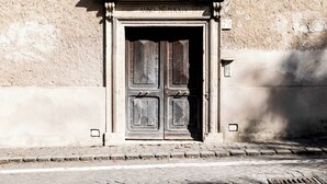 A weathered wooden door with a plaque above it, set in a stone wall.