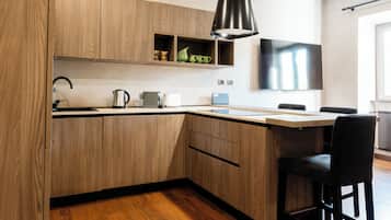 Una cocina moderna con armarios de madera, una lámpara colgante negra, una computadora portátil y un televisor de pantalla plana.
