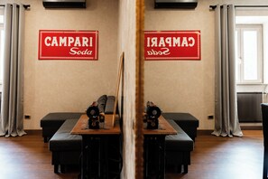Ein Zimmer mit einer Spiegelwand, zwei schwarzen Sofas, einem Holztisch und einer Heizung.