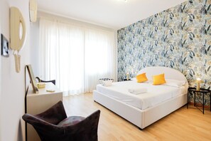 Ein Schlafzimmer mit einem großen Bett, einem Schreibtisch mit Stuhl, einem Spiegel und einer Wand mit Muster.