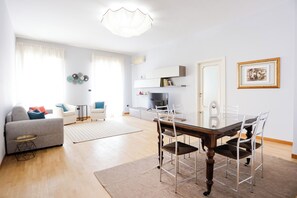A modern living room with a dining table, chairs, a sofa, and a TV. - Riviera di Chiaia 207 - 7° Piano (Naples)