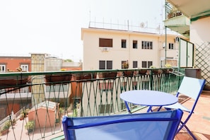 A balcony with a blue chair and a small table, overlooking a building with multiple windows and balconies. - Riviera di Chiaia 207 - 7° Piano (Naples)