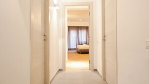 A hallway leading to a bedroom with a bed, curtains, and a ceiling light fixture. - Domus Solis (Rome)