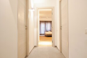 A hallway leading to a bedroom with a bed, curtains, and a ceiling light fixture. - Domus Solis (Rome)