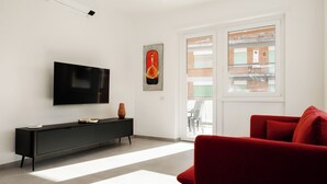A modern living room with a flat-screen TV, a black console, a red sofa, and a large window with a view of a building. - Domus Solis (Rome)