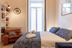 A hotel room with a bed, a sofa, a bookshelf, and a door. - Palazzo Guida al Duomo (Naples)