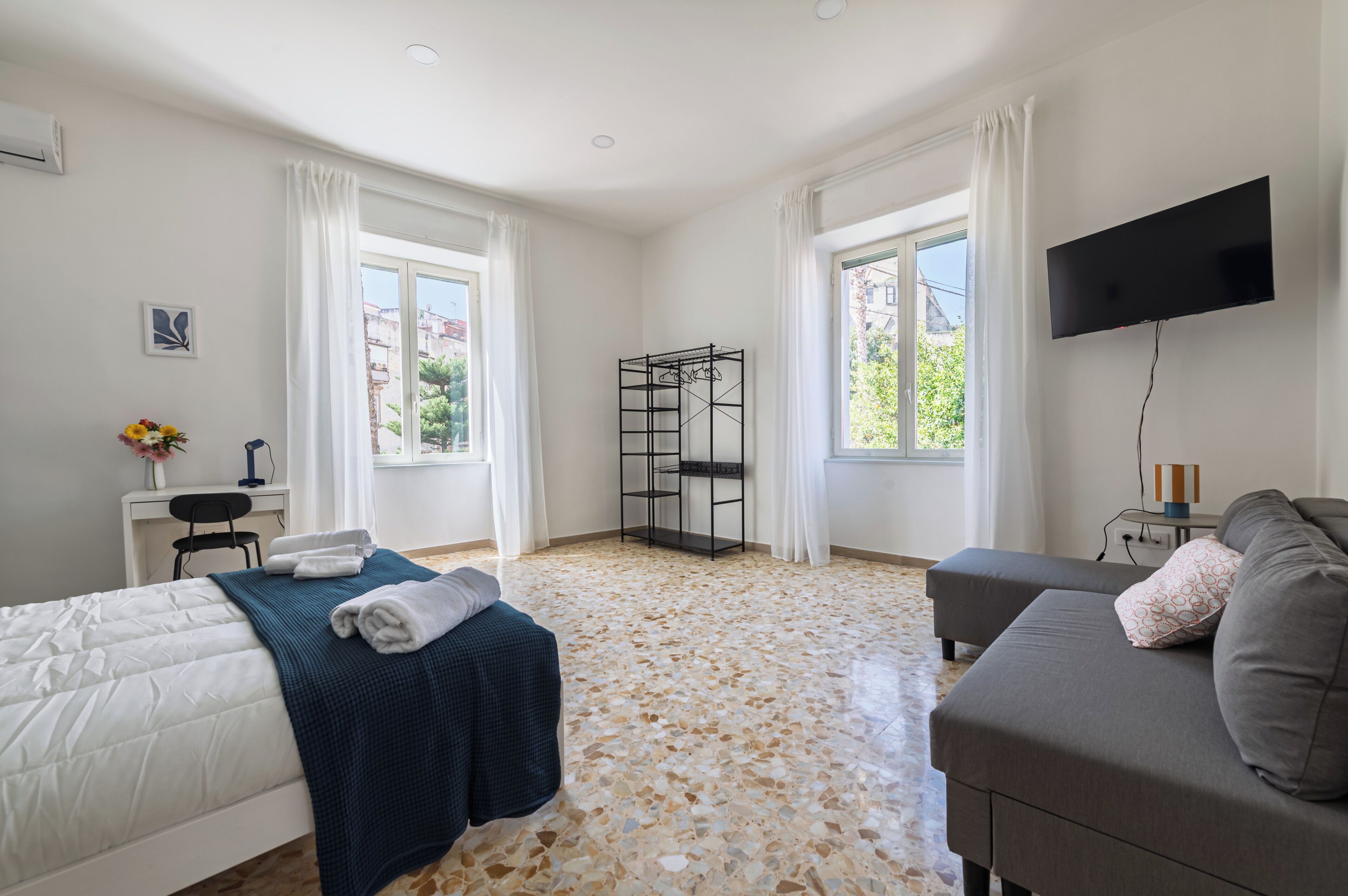 Une chambre avec un lit, un canapé, une télévision, un bureau et une fenêtre.