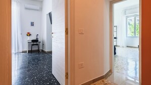 En hall med ett skrivbord, en stol och en liten vas med blommor.