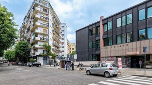 A multi-story building with balconies, a modern building with large windows, and a crosswalk with cars and pedestrians. - La Favola di San Martino (Naples)