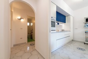 A modern kitchen with white cabinets, a blue accent wall, and a built-in oven. - La Favola di San Martino (Naples)