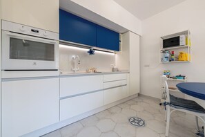 Eine moderne Küche mit weißen Schränken, einer blauen Arbeitsplatte und einer Mikrowellenregal.