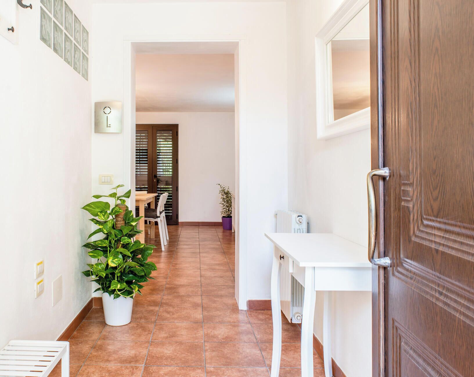 Un pasillo con comedor, una planta en maceta y una puerta.