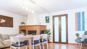A modern living room with a dining area, a fireplace, and a large window. - Casa Corallo (Baratili San Pietro)