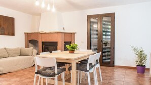 A dining area with a wooden table and chairs, a sofa, a fireplace, and a door with blinds. - Casa Corallo (Baratili San Pietro)