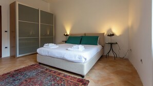 A neatly made bed with folded towels, a green pillow, and two bedside lamps. - Vico Santa Maria del Pozzo 9 (Naples)