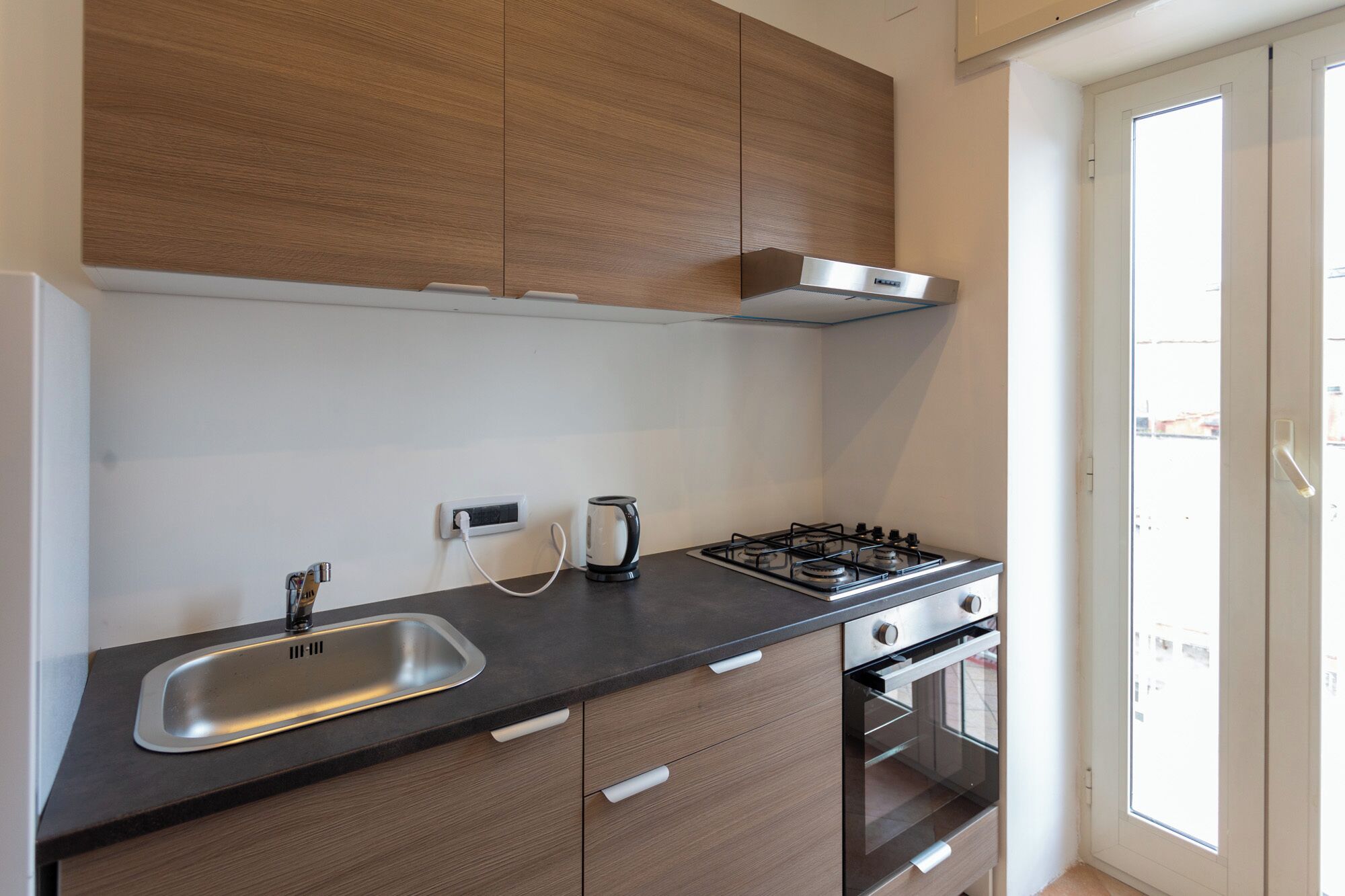 A modern kitchen with a gas stove, a sink, and a built-in oven.