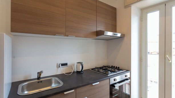 A modern kitchen with a gas stove, a sink, and a built-in oven. - Vico Santa Maria del Pozzo 9 (Naples)