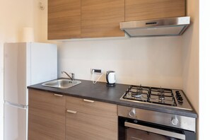 A compact kitchen with a gas stove, a kettle, and a built-in oven. - Vico Santa Maria del Pozzo 9 (Naples)