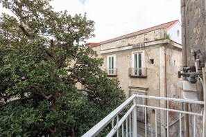 Un bâtiment doté d’une façade en pierre, de deux fenêtres à encadrements blancs et d’un balcon.