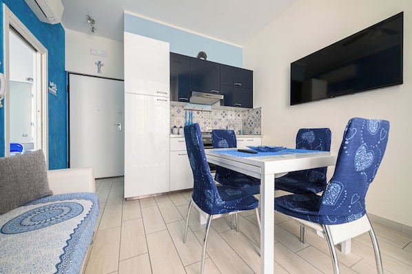 Una cocina compacta con armarios blancos, una encimera negra y un mantel azul estampado.