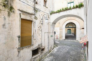 A narrow cobblestone street with an arched entrance and a shuttered window. - Luci D'artista (Vietri sul Mare)