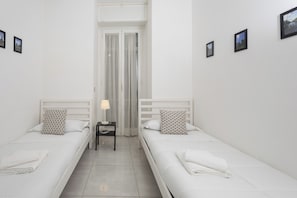 A twin room with two single beds, a nightstand with a lamp, and a window with curtains. - Civico 79 (Naples)