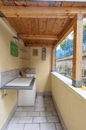 Ein kleines, abgeschlossenes Badezimmer mit Holzbalkendecke, einem Waschbecken und einem Fenster mit Blick auf eine Steinmauer.