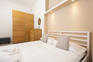 A modern bedroom with a large bed, wooden wardrobe, and a bench. - Civico 79 (Naples)