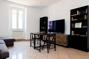 Una sala de estar moderna con un sofá, una mesa con sillas, un televisor y una estantería.