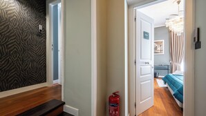 A hallway with a zebra-patterned wall, a fire extinguisher, and a bedroom with a blue bed and curtains. - Zapata Relais - Chiaia (Naples)