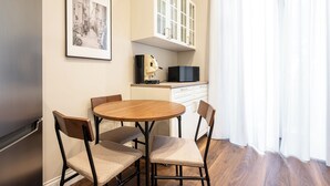 A small dining area with a round wooden table and four chairs, a microwave, and a cabinet above the counter. - Casa Eva - 18 (Naples)